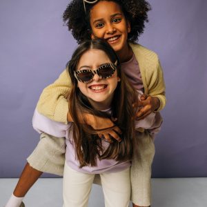 Two girls enjoying a playful piggyback ride, laughing and having fun together.